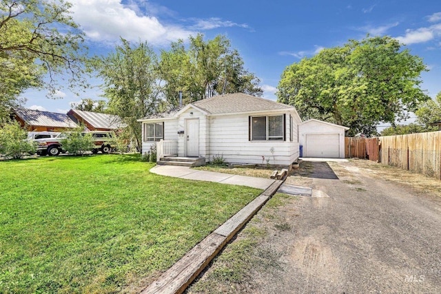 view of front of home with driveway, a front yard, fence, and a detached garage