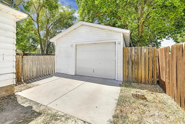 detached garage with concrete driveway and fence