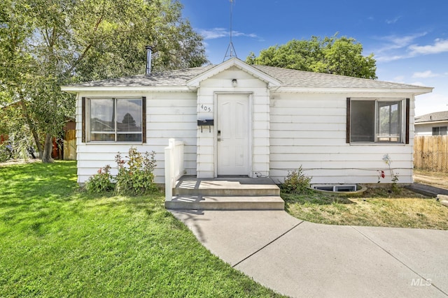 bungalow-style home featuring a shingled roof, fence, and a front yard