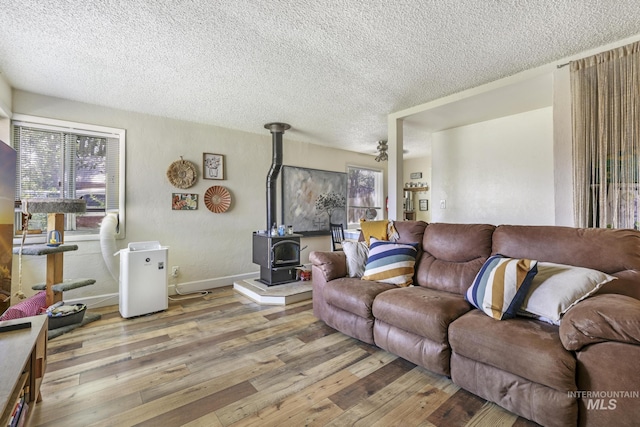 living area with a textured ceiling, hardwood / wood-style floors, plenty of natural light, and a wood stove