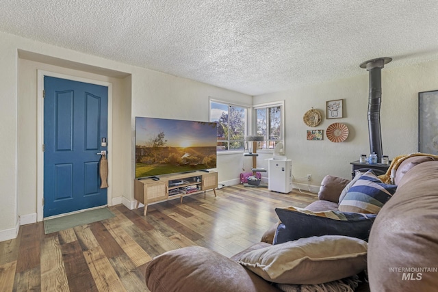 living area with a wood stove, hardwood / wood-style flooring, baseboards, and a textured ceiling