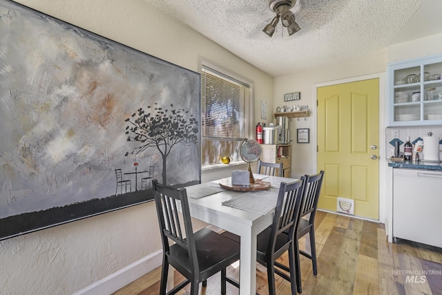 dining room with a textured ceiling, ceiling fan, wood finished floors, and baseboards