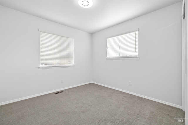 carpeted spare room featuring visible vents and baseboards