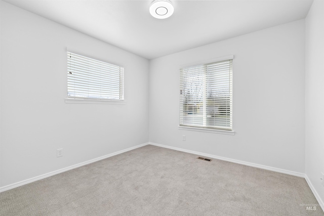 carpeted empty room with visible vents and baseboards