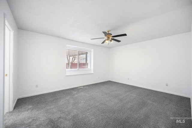 spare room with baseboards, dark carpet, and a ceiling fan