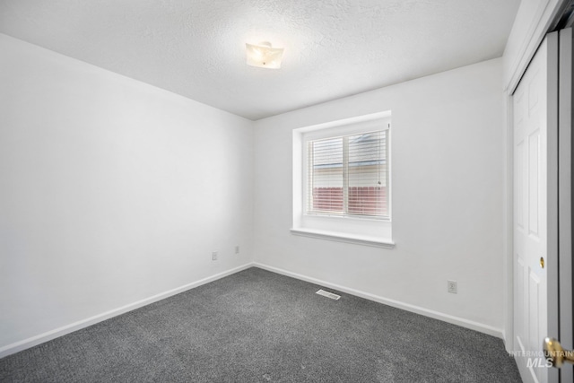 unfurnished bedroom featuring baseboards, visible vents, a textured ceiling, dark carpet, and a closet