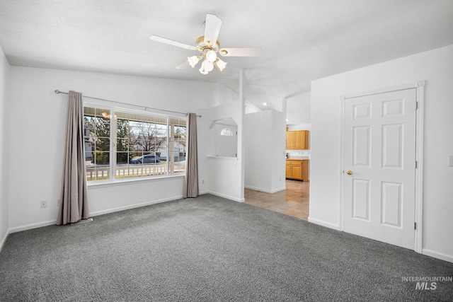 spare room featuring lofted ceiling, baseboards, a ceiling fan, and light colored carpet