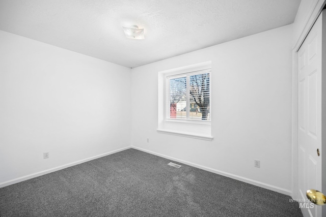 unfurnished bedroom featuring a closet, dark carpet, visible vents, and baseboards