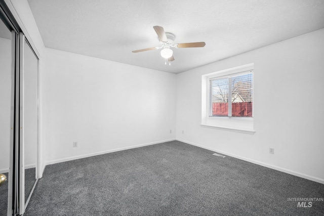 unfurnished bedroom featuring dark colored carpet, a closet, visible vents, and baseboards