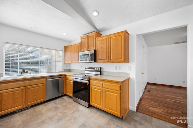 kitchen featuring baseboards, visible vents, stainless steel appliances, light countertops, and a sink