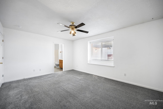 unfurnished bedroom featuring baseboards, a ceiling fan, ensuite bathroom, carpet, and a textured ceiling