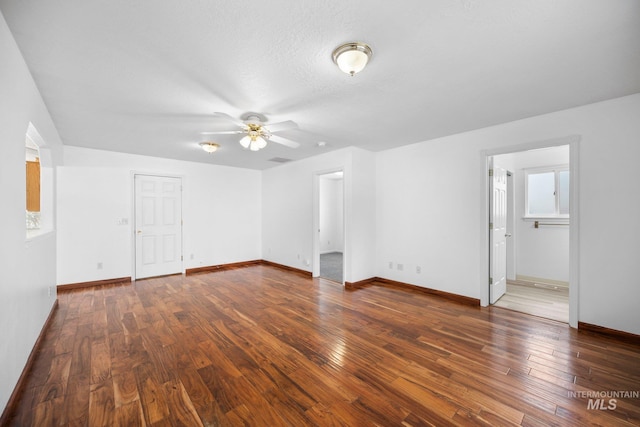 empty room featuring wood-type flooring, a ceiling fan, and baseboards