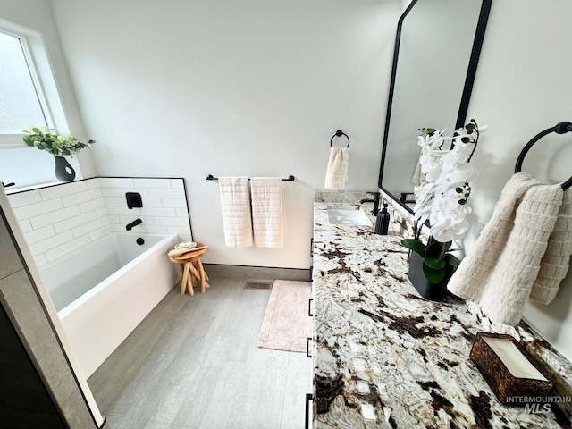 bathroom with vanity, a tub to relax in, and wood-type flooring