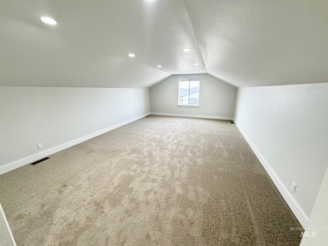 bonus room with lofted ceiling and carpet flooring