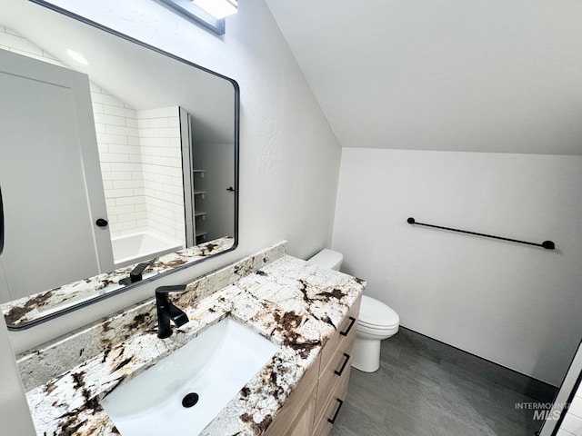 bathroom featuring vanity, toilet, vaulted ceiling, and wood-type flooring