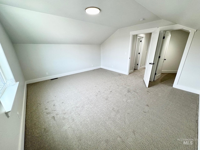 additional living space featuring vaulted ceiling and light carpet