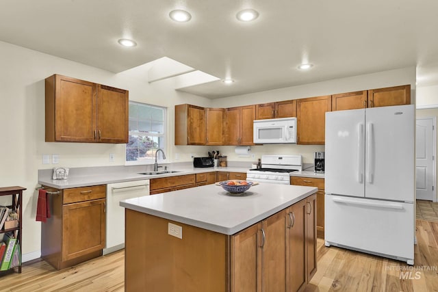 kitchen featuring a kitchen island, white appliances, light countertops, and a sink