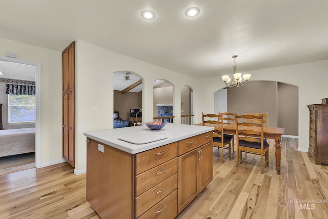 kitchen with light wood finished floors, light countertops, hanging light fixtures, brown cabinetry, and a kitchen island