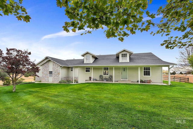 cape cod home featuring fence, a front lawn, and a patio