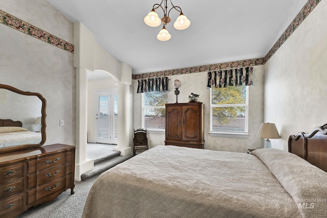 bedroom with light carpet, multiple windows, arched walkways, and an inviting chandelier