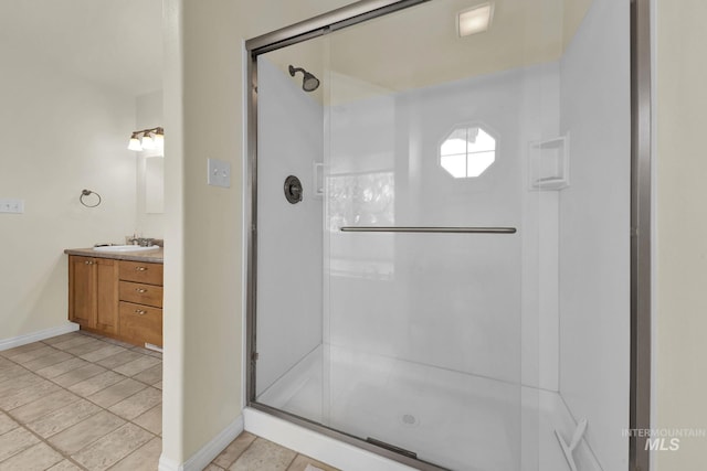 bathroom with a stall shower, baseboards, and vanity