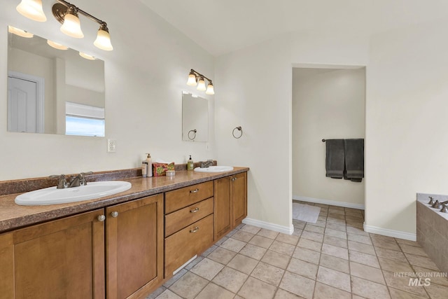 bathroom featuring double vanity, tile patterned flooring, a sink, and baseboards