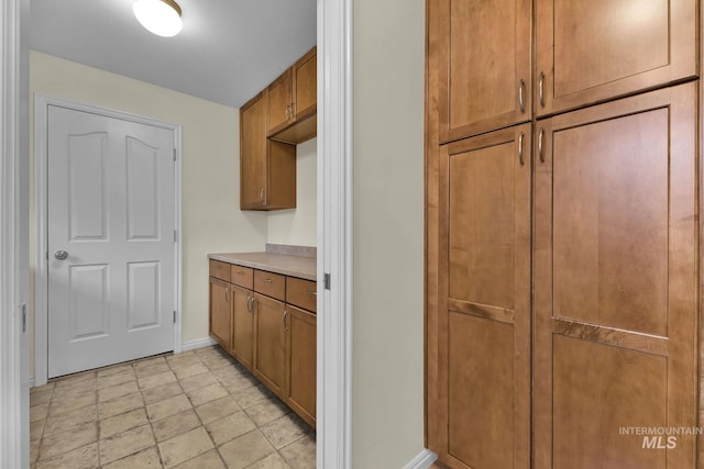 kitchen with light countertops, brown cabinetry, and baseboards