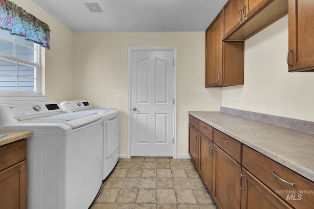 washroom featuring cabinet space, washing machine and dryer, visible vents, and baseboards