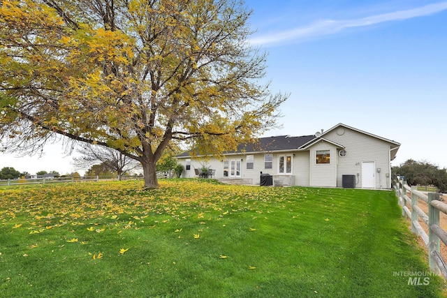 rear view of house featuring fence and a lawn