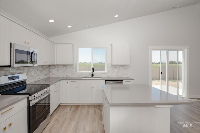 kitchen with sink, white cabinetry, vaulted ceiling, and stainless steel appliances