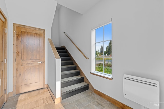 staircase featuring plenty of natural light and heating unit