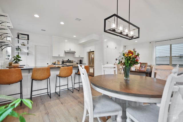 dining space featuring light hardwood / wood-style flooring and an inviting chandelier