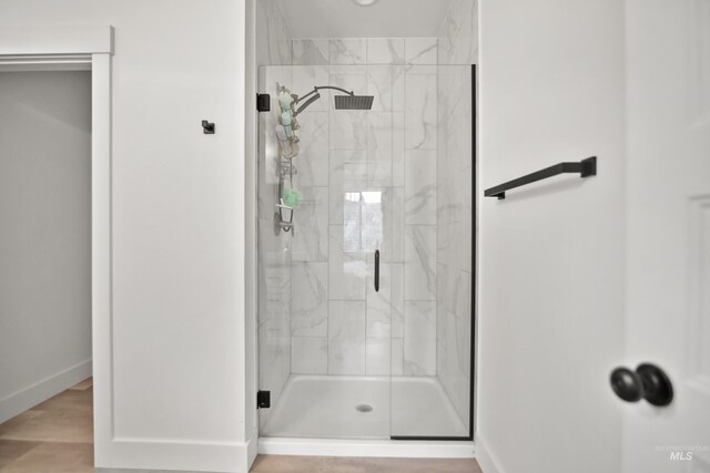 bathroom with a shower with shower door and wood-type flooring