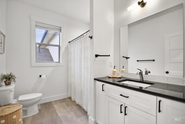 bathroom with toilet, wood-type flooring, and vanity