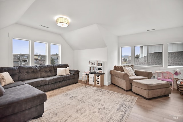 living room featuring a healthy amount of sunlight, light wood-type flooring, and vaulted ceiling