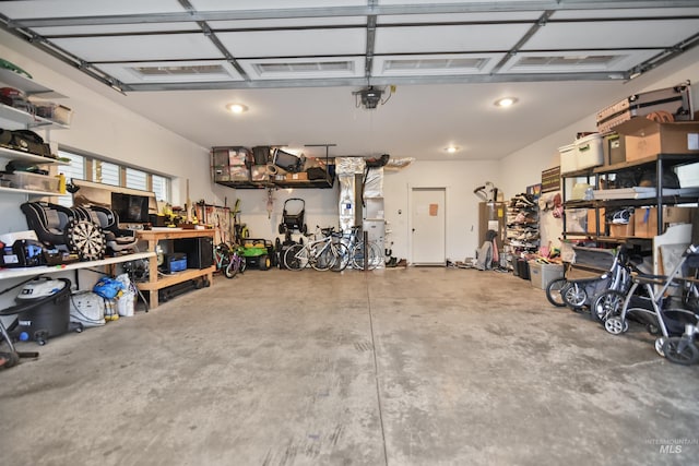 garage featuring a garage door opener, a workshop area, and strapped water heater