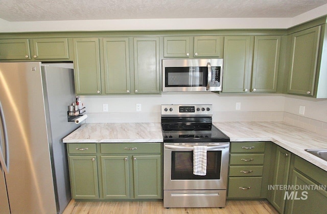 10382 Scout Ridge St, Nampa, ID 83687 - kitchen with green cabinetry, appliances with stainless steel finishes, light wood-type flooring, and light stone countertops