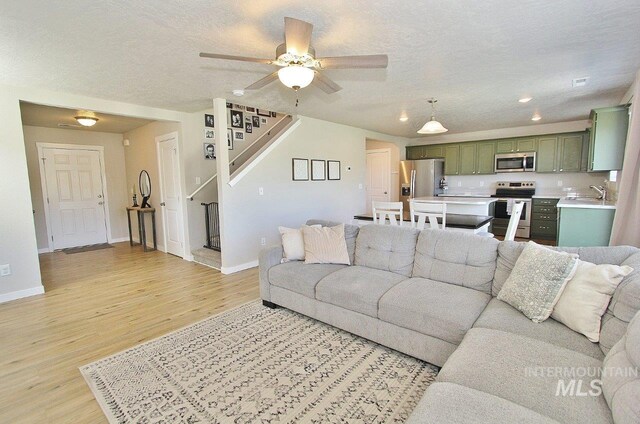 10382 Scout Ridge St, Nampa, ID 83687 - living area featuring light wood-style flooring, stairway, ceiling fan, baseboards, and recessed lighting