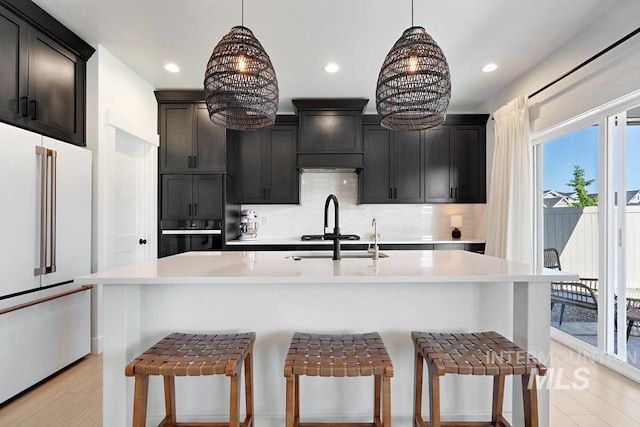 12524 W Shortcreek, Star, ID 83669 - kitchen featuring high end fridge, black oven, decorative backsplash, light countertops, and a breakfast bar