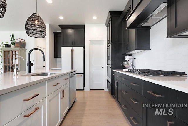 12524 W Shortcreek, Star, ID 83669 - kitchen with appliances with stainless steel finishes, range hood, light countertops, light wood-style flooring, and hanging light fixtures