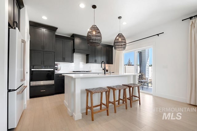 12524 W Shortcreek, Star, ID 83669 - kitchen with black appliances, tasteful backsplash, light wood-style floors, a kitchen bar, and light countertops