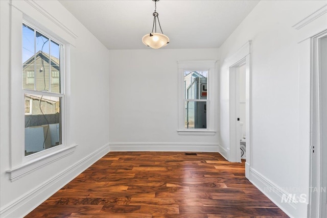 unfurnished room featuring a healthy amount of sunlight, baseboards, and wood finished floors