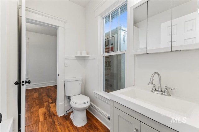 bathroom featuring toilet, vanity, baseboards, and wood finished floors