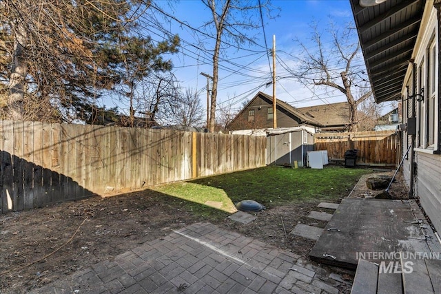 view of yard featuring an outdoor structure, a fenced backyard, and a patio area