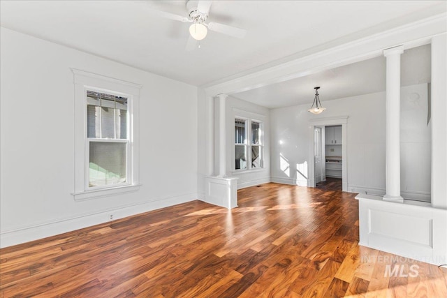 unfurnished room with a ceiling fan, decorative columns, and wood finished floors