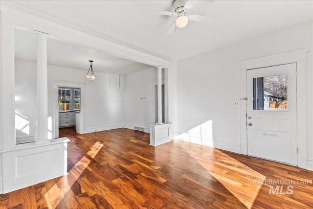 foyer featuring visible vents, baseboards, ceiling fan, decorative columns, and wood finished floors