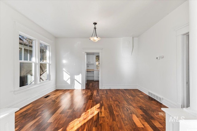 unfurnished dining area with visible vents, baseboards, and wood finished floors