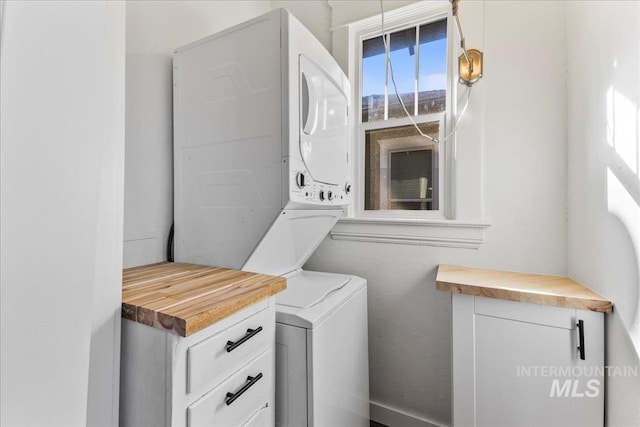 laundry room with cabinet space and stacked washer and clothes dryer