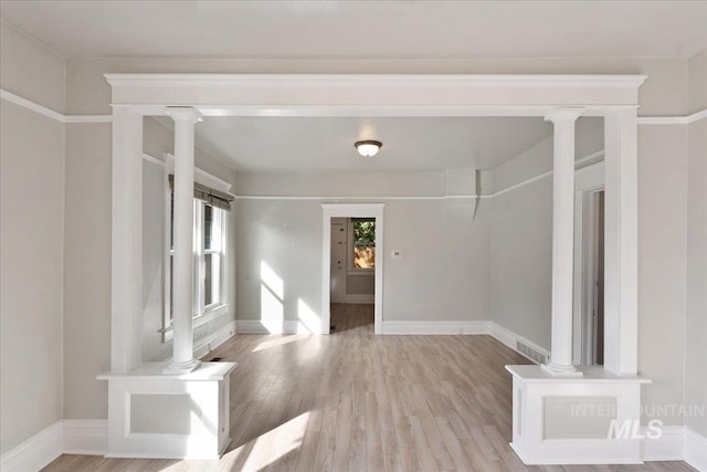 interior space with wood finished floors, visible vents, ornate columns, and baseboards