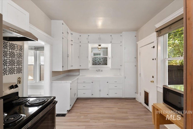 kitchen featuring electric range oven, light countertops, under cabinet range hood, white cabinetry, and light wood-type flooring